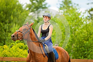 Jockey girl doing horse riding on countryside meadow