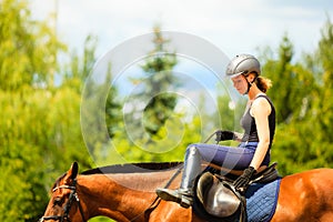 Jockey girl doing horse riding on countryside meadow