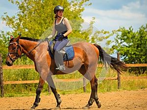 Jockey girl doing horse riding on countryside meadow