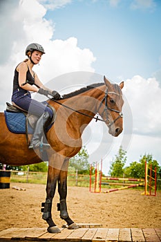 Jockey girl doing horse riding on countryside meadow