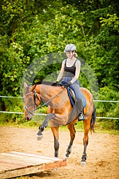 Jockey girl doing horse riding on countryside meadow