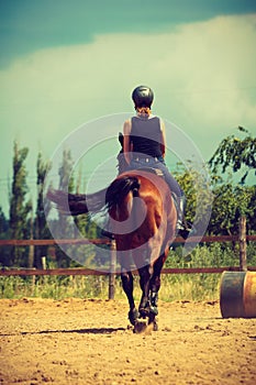 Jockey girl doing horse riding on countryside meadow