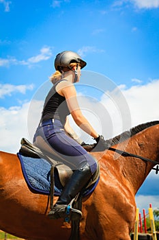 Jockey girl doing horse riding on countryside meadow