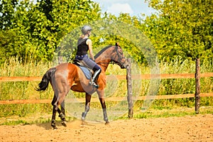 Jockey girl doing horse riding on countryside meadow