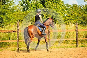 Jockey girl doing horse riding on countryside meadow