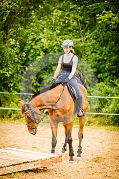 Jockey girl doing horse riding on countryside meadow