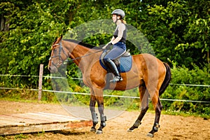 Jockey girl doing horse riding on countryside meadow