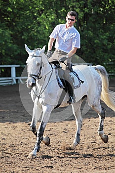 Jockey in glasses with whip riding horse