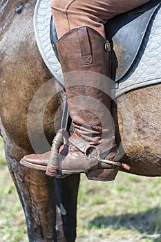 Jockey riding boot in the stirrup. Man riding a brown horse