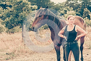 Jockey woman walking with horse on meadow