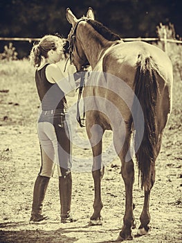 Jockey woman walking with horse on meadow