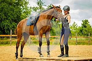 Jockey young woman getting horse ready for ride