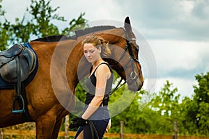 Jockey young woman getting horse ready for ride