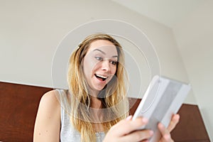 Jocund girl using tablet and sitting in bed.