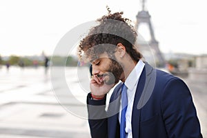 Jocund mulatto guy raving near Eiffel Tower and calling friend b