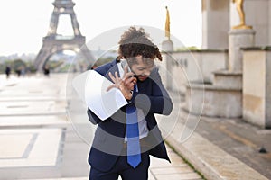 Jocund mulatto guy raving near Eiffel Tower and calling friend b