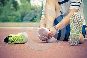 Jogger checking if his ankle is broken or twisted