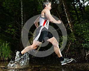 Jogger in a jump through a streambed