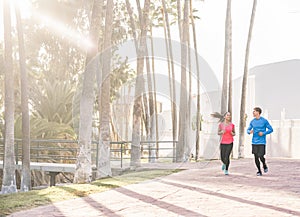 Joggers couple running outdoor in city track together - Sporty happy people training at morning in tropical place - Healthy