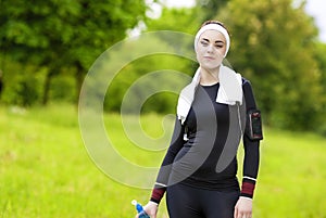 Jogging and Fitness Concept:Portrait of Smiling Caucasian Fit Woman Drinking Water Outdoors and Smiling.