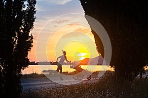 Jogging mother with stroller enjoying motherhood at sunset lands