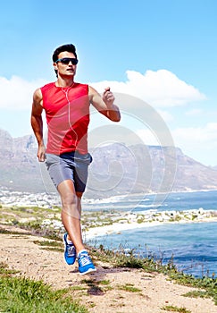 Jogging with an ocean view. a handsome young male athlete jogging outdoors.