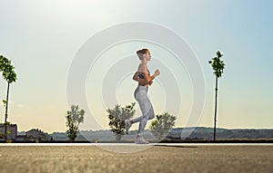 Jogging run. Strong athletic woman running on black background wearing in the sportswear. Fitness and sport motivation