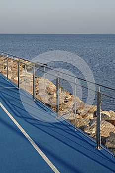 Jogging running lanes with white lines, blue artificial textured ground. Handrails and stones by the side. Natural
