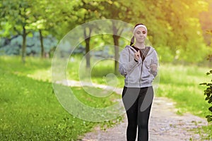 Jogging Sport Concept: Young Running Fitness Woman Training Outdoor in the Forest While LIstening to Music