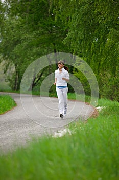 Jogging - sportive woman running on road in nature