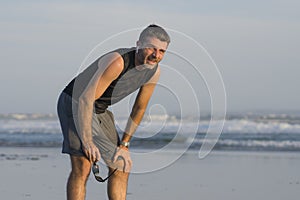 Jogging Summer workout - young attractive and fit runner man training on beautiful beach breathing tired and exhausted cooling off