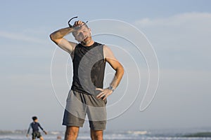 Jogging Summer workout - young attractive and fit runner man training on beautiful beach breathing tired and exhausted cooling off