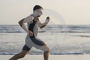 Jogging Summer workout - young attractive and fit runner man training on beautiful beach running barefoot free and happy by the