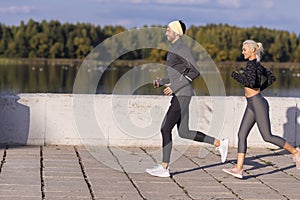 Jogging Training. Two Positive Caucasian Runners Athletes Training Together During Running Fitness Exercise At River Outside as