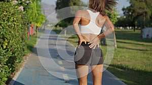 Jogging woman experiences lower back pain during a run. Watch your back.