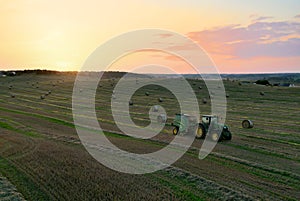 John Deere Tractor 6715R with John Deere V461R round baler making Hay Bales in an agricultural field. Farm Round Hay Bale Tractor