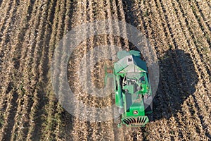 A John Deere W550 combine is harvesting corn on the field on a sunny day