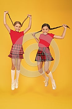 Join celebration. School uniform. Scottish style. Cheerful friends schoolgirls jumping yellow background. Celebrate