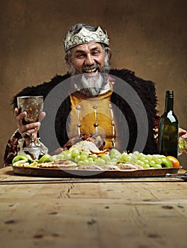 Join me for a royal feast. A mature king feasting alone in a banquet hall.