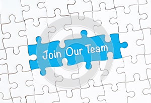 Join our team concept. White jigsaw puzzle with word and blue background