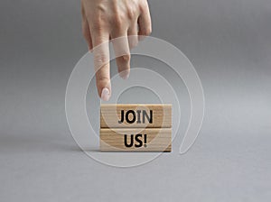 Join us symbol. Concept word Join us on wooden blocks. Beautiful grey background. Businessman hand. Business and Join us concept.