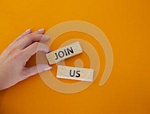 Join us symbol. Concept word Join us on wooden blocks. Beautiful orange background. Businessman hand. Business and Join us concept