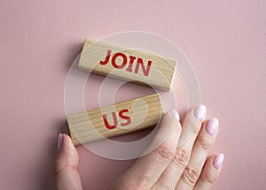Join us symbol. Concept word Join us on wooden blocks. Beautiful pink background. Businessman hand. Business and Join us concept.
