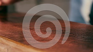 A joiner applies a wood impregnation to a wood product. a man covers a wooden shelf with oil for wood