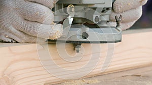 Joiner cuts off the sharp corners of a wooden beam using a milling machine