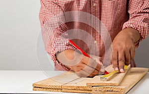 Joiner measuring a wooden plank with tape measure yellow on the work-table for construction, carpenter Use tool checking accuracy