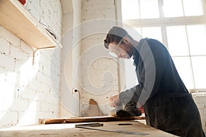 Joiner polishes wooden board in workshop