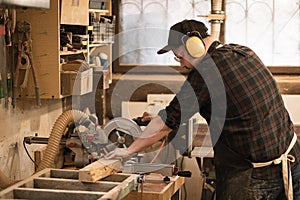 Joiner worker, businessman in protective apron and headphones use modern grinder machine to process cutting wood boards