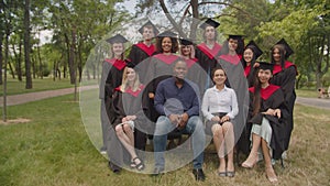 Joint portrait of academic staff and multiracial graduates outdoors