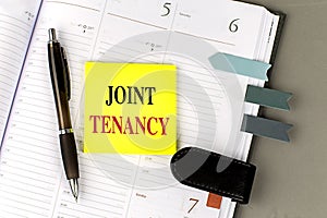 JOINT TENANCY text sticky on dairy on gray background photo